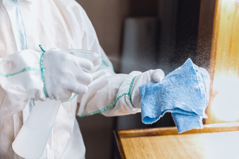 Close-up of a professional using a wiping cloth to disinfect a surface in a clinical setting